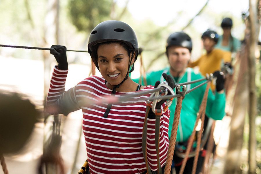Adventure and Entertainment Insurance - Friends Wearing Helmets and Protective Great While Enjoying a Zip-Line in an Adventure in Park